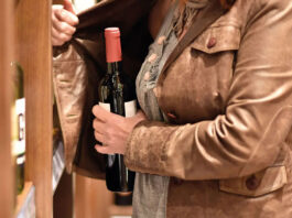 Shoplifting on the rise in Scotland A woman hiding a bottle under her jacket in a store.