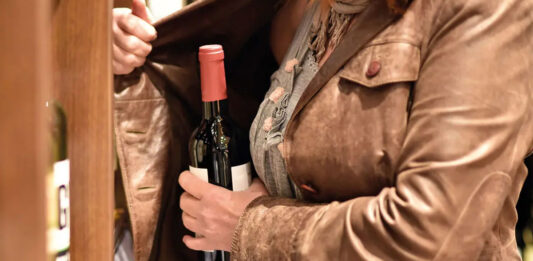 Call for action as shoplifting in Scotland soars A woman hiding a bottle under her jacket in a store.