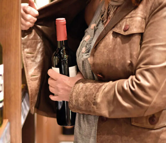 Shoplifting on the rise in Scotland A woman hiding a bottle under her jacket in a store.