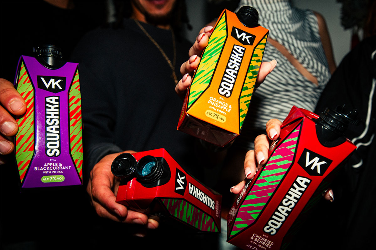 A group of people hold bottles of VK Squashka up to the camera.