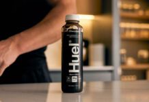 Danone set to acquire Huel meal solutions A bottle of Huel Chocolate Black Edition sits on a countertop with a person behind the bottle.