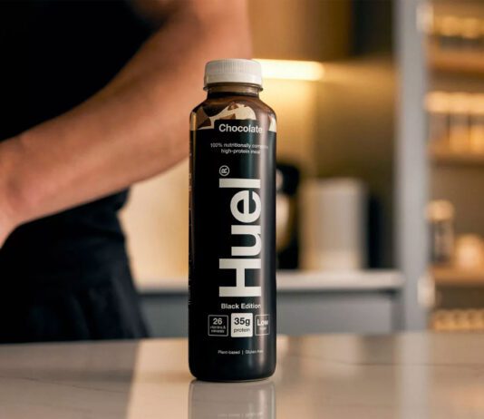 Danone set to acquire Huel meal solutions A bottle of Huel Chocolate Black Edition sits on a countertop with a person behind the bottle.