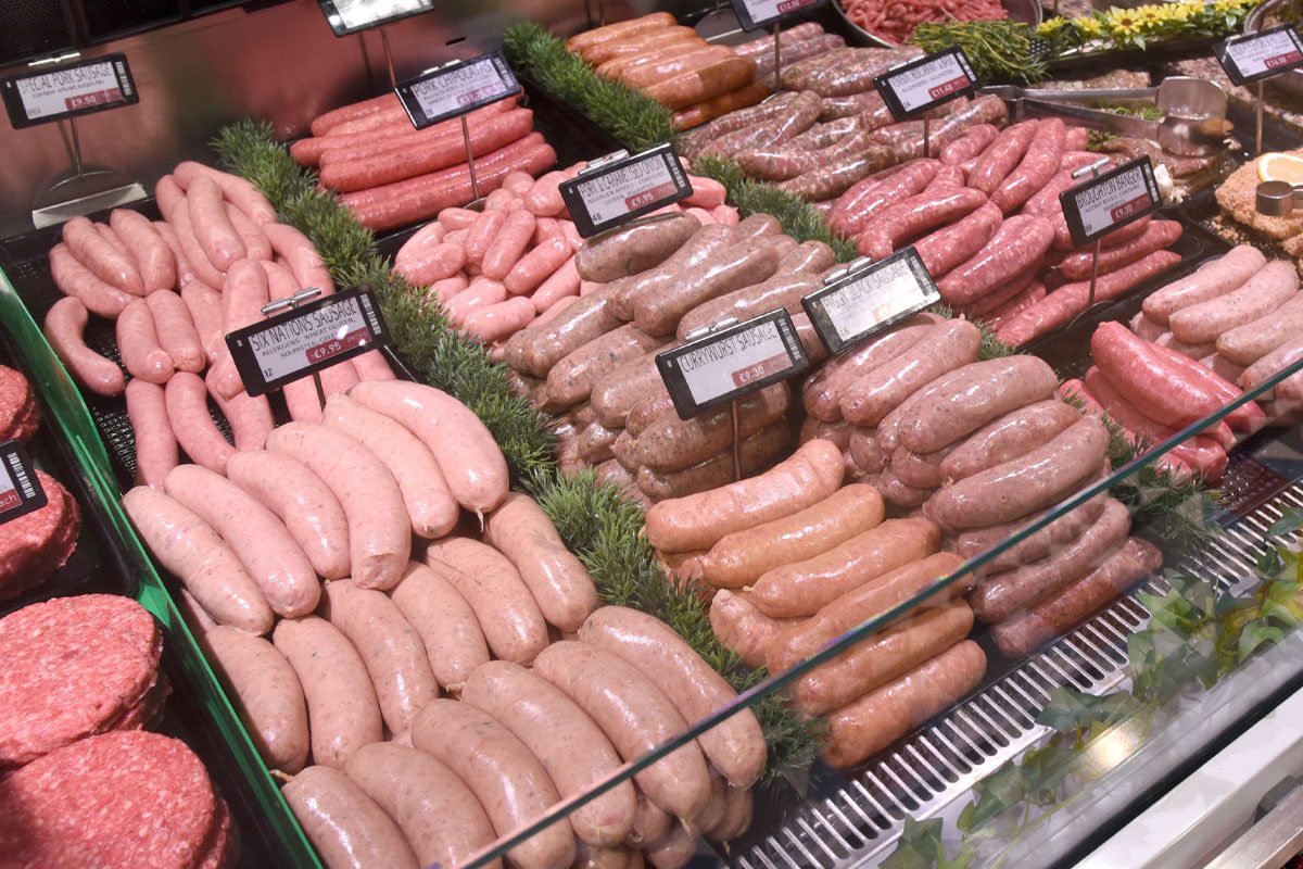 A butchery counter featuring a range of meat products including burgers and sausages.