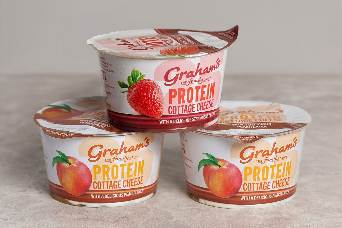 Pots of Graham's The Family Dairy's Cottage Cheese with Fruit Layers have been stacked up in a pyramid formation against a grey background.