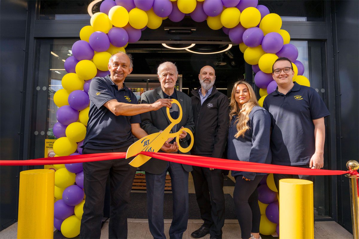 A group of people open Jet Restalrig in Edinburgh using a pair of novelty scissors to cut a ribbon.