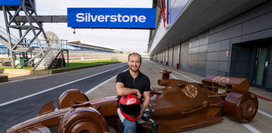 KitKat revs up for F1 season with life-sized chocolate car Billy Monger, former F1 driver, sits in front of a life-sized chocolate F1 car with the KitKat logo on it and the starting line of Silverstone Circuit.