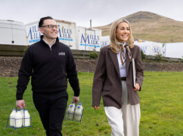 Mills Milk targets further expansion after £24m turnover result Members of the Mills Milk team stand in a field with branded vans behind them and a hill in the distance.