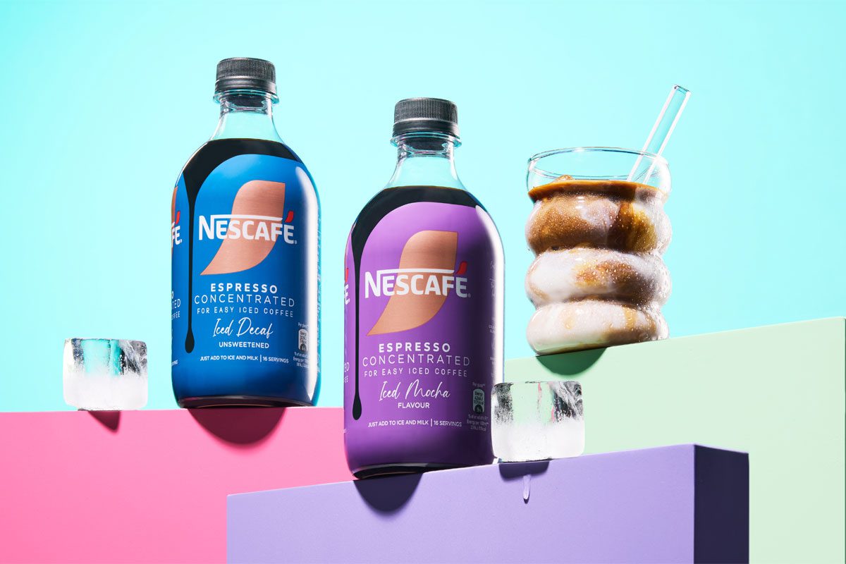 Bottles of Nescafé Espresso Concentrated Mocha and Decaf variants are stacked up on pastel coloured boxes with an iced coffee serve next to them.