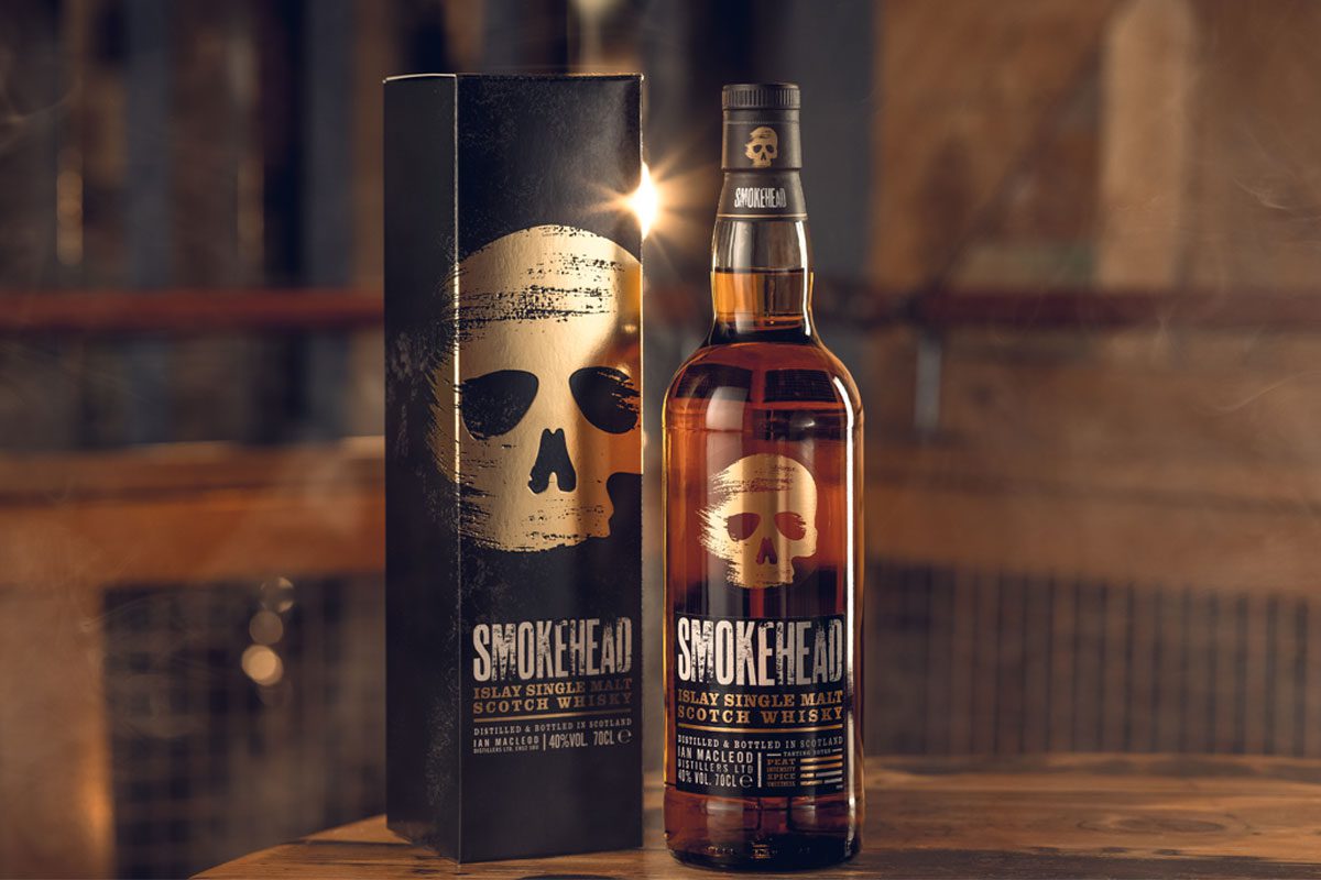 A bottle and outer box of Smokehead whisky stand on a table.
