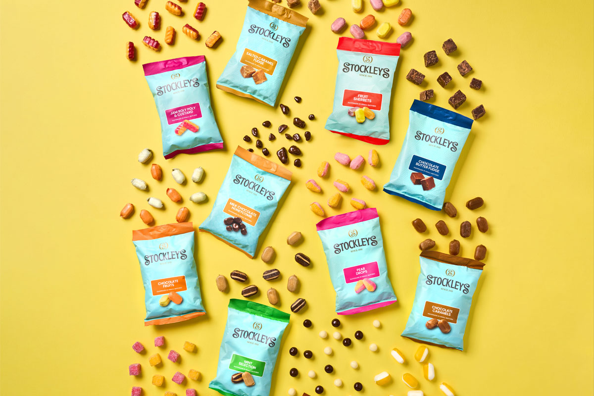 Bags of Stockleys sweets with sweets pouring out from them against a yellow background.