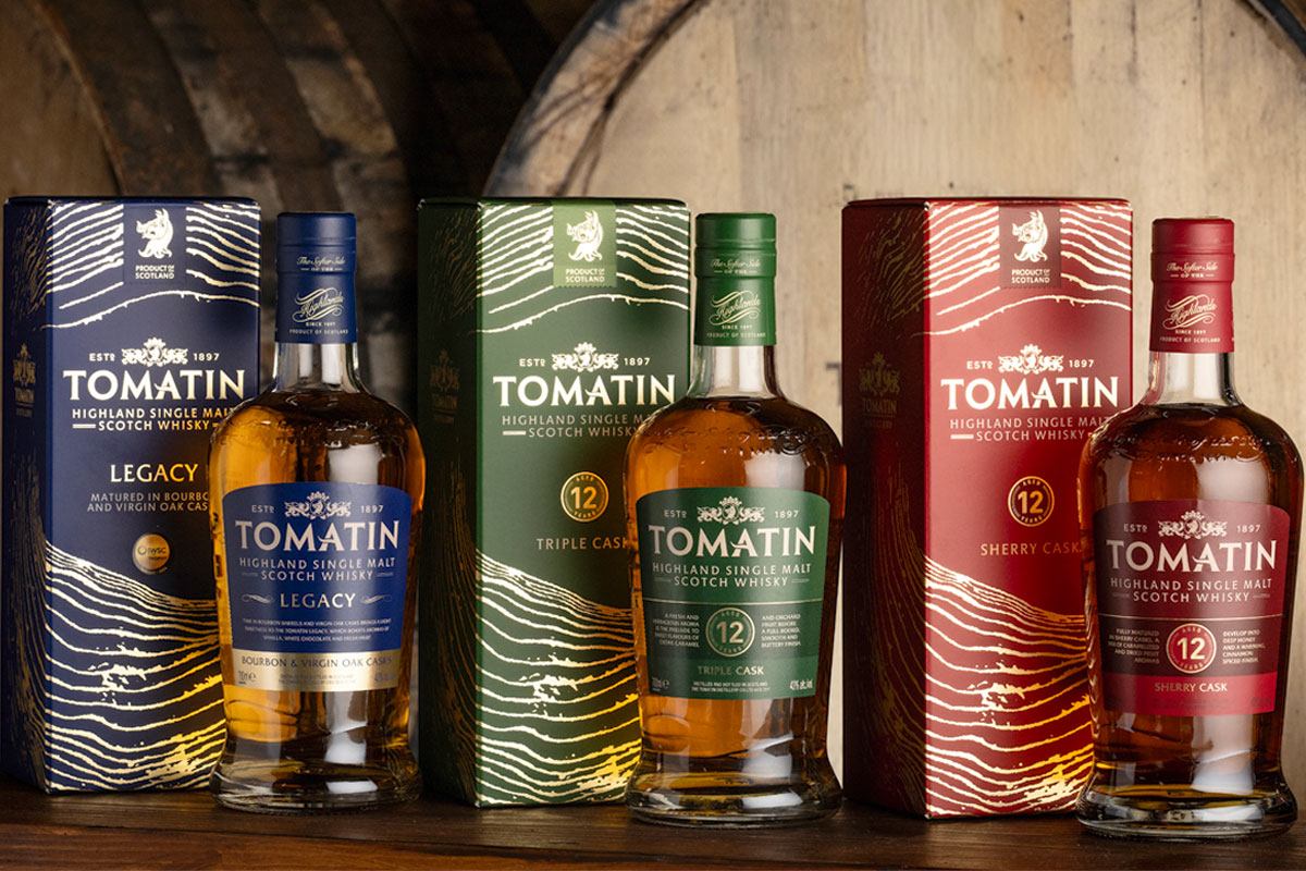 Bottles of Tomatin featuring the 2026 redesign with whisky casks behind the bottles.