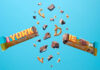 Yorkie unveils new Salted Caramel Pretzel bar A Yorkie Salted Caramel Pretzel bar is broken in two with pieces flying out from it against a blue background.