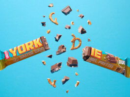 Yorkie unveils new Salted Caramel Pretzel bar A Yorkie Salted Caramel Pretzel bar is broken in two with pieces flying out from it against a blue background.