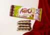 Aero takes to the runway with new Pistachio flavour A pack of Aero Pistachio is balanced on top of bars of the chocolate with a red fabric draped behind it.