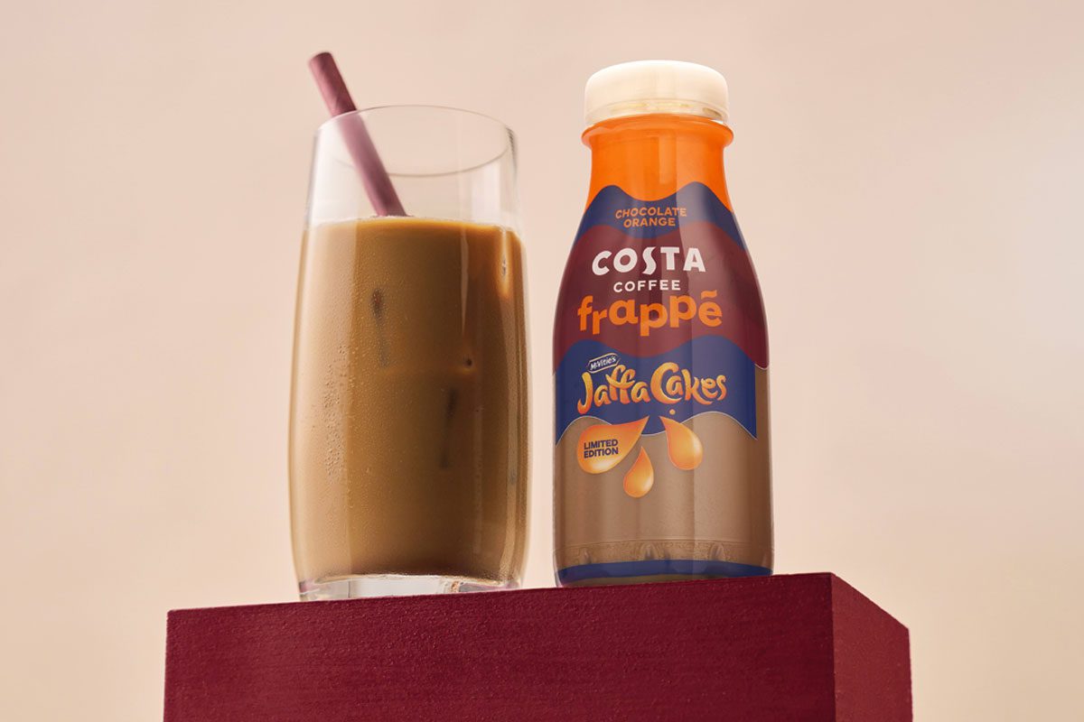 A bottle of Costa Coffee Frappé Jaffa Cakes stands next to a glass with the drink inside.