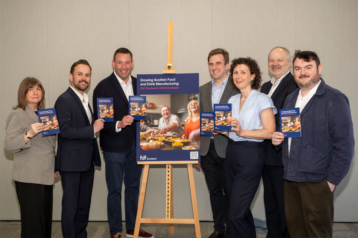 A group of politicians stand around an easel with an advert for the Food & Drink Federation Scotland on it.