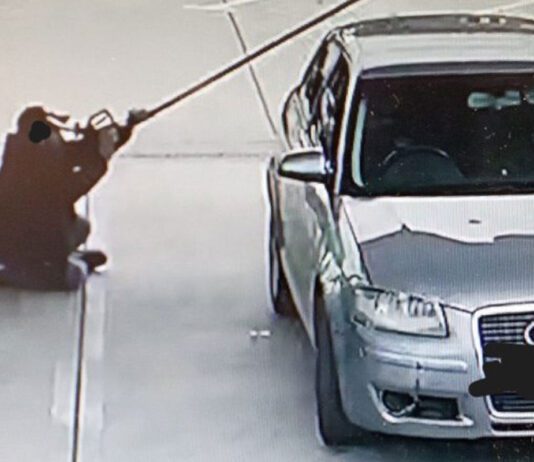 Fuel value losses increase across forecourts A person sits in a forecourt fuel station holding a fuel nozzle up close to their face.