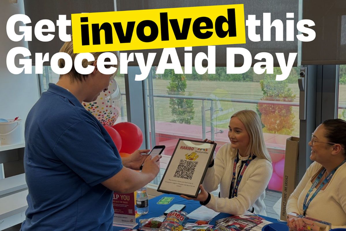 A person attends a Haribo stand to scan a QR code with the slogan 'Get involved this GroceryAid Day'.