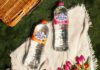 Highland Spring unveils new Flavoured Water range Bottles of Highland Spring Orange & Passionfruit and Summer Berries lie on a picnic scene with a wicker basket in the background.