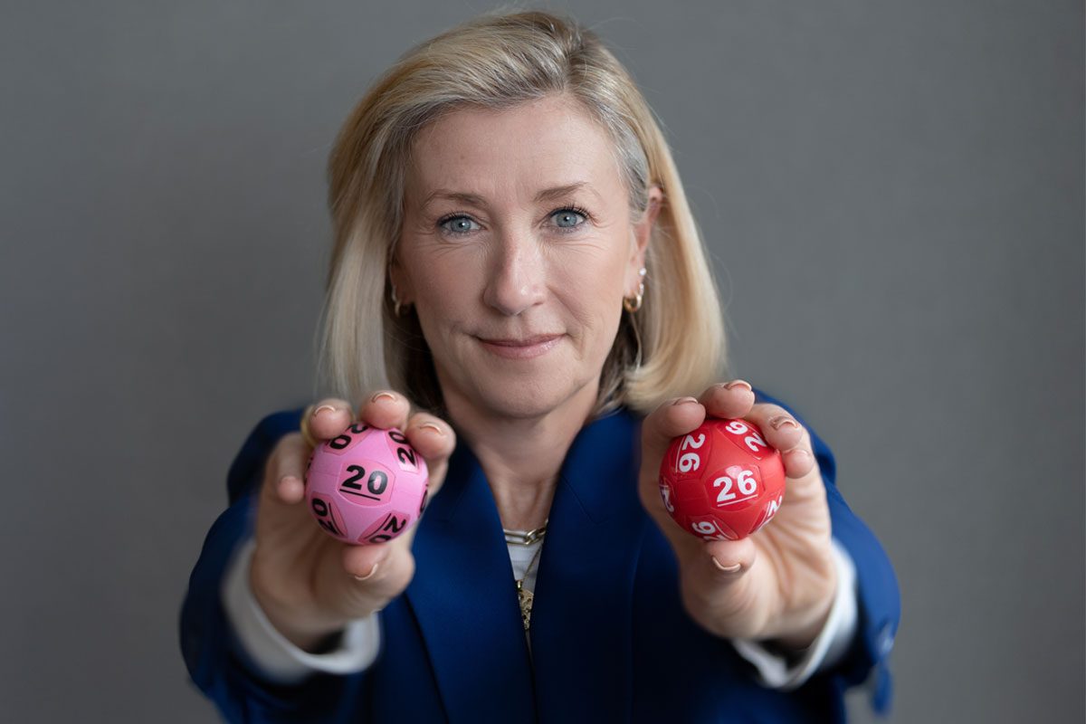 Andria Vidler, chief executive at Allwyn UK, holds two lottery balls with a 20 and a 26 on them.