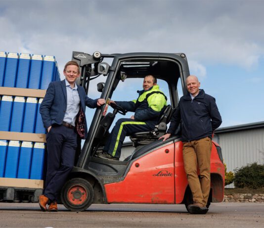Mackie’s acquires new facility to grow distribution capacity L–R Stuart Common, MD at Mackie's, Roddy Adam, site supervisor, and Mac Mackie, chairperson, are gathered round a forklift truck that is carrying Mackie's ice cream containers.