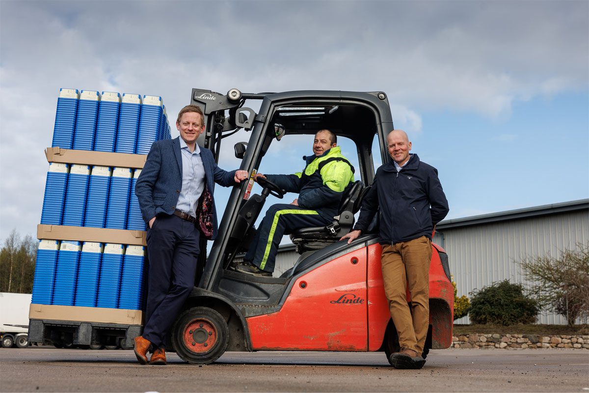 L–R Stuart Common, MD at Mackie's, Roddy Adam, site supervisor, and Mac Mackie, chairperson, are gathered round a forklift truck that is carrying Mackie's ice cream containers.