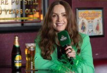 Magners set to ‘Share the Craic’ this summer Emma Doran sits in a pub with pint of Magners cider and a bottle on the table next to her.