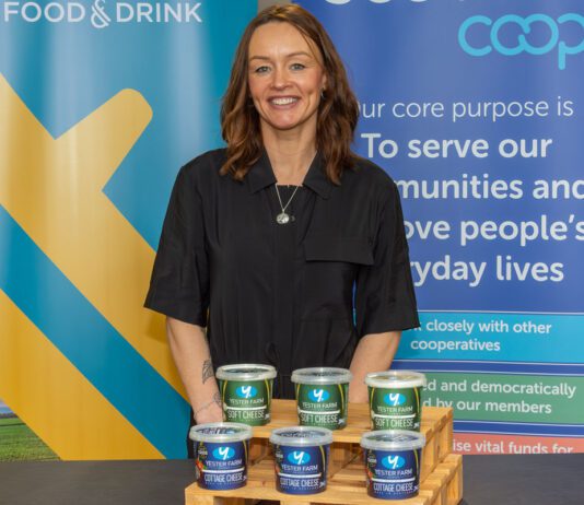 Yester Farm Dairies rolls out in Scotmid stores A woman stands behind a table with pots of Yester Farm Dairies Cottage Cheese on it.