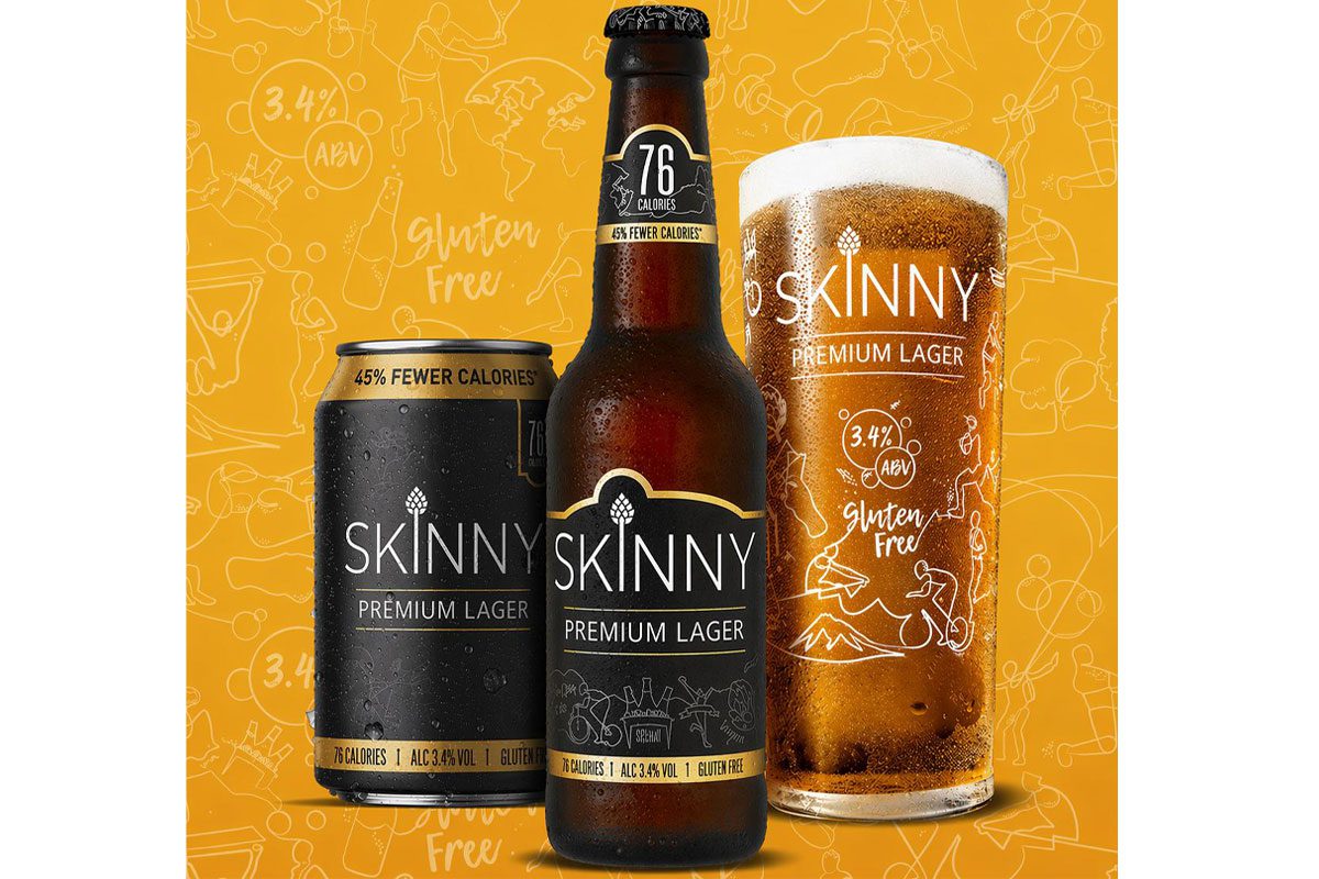 A can, a bottle and a pint glass of Skinny Brands lager stand against a yellow background.