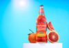 Thatchers introduces new Blood Orange 0.0% cider A bottle of Thatchers Blood Orange 0.0% stands on a white podium with blood oranges around it with a sunny background.