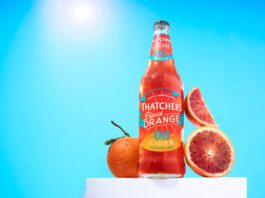 Thatchers introduces new Blood Orange 0.0% cider A bottle of Thatchers Blood Orange 0.0% stands on a white podium with blood oranges around it with a sunny background.