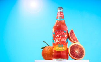 Thatchers introduces new Blood Orange 0.0% cider A bottle of Thatchers Blood Orange 0.0% stands on a white podium with blood oranges around it with a sunny background.