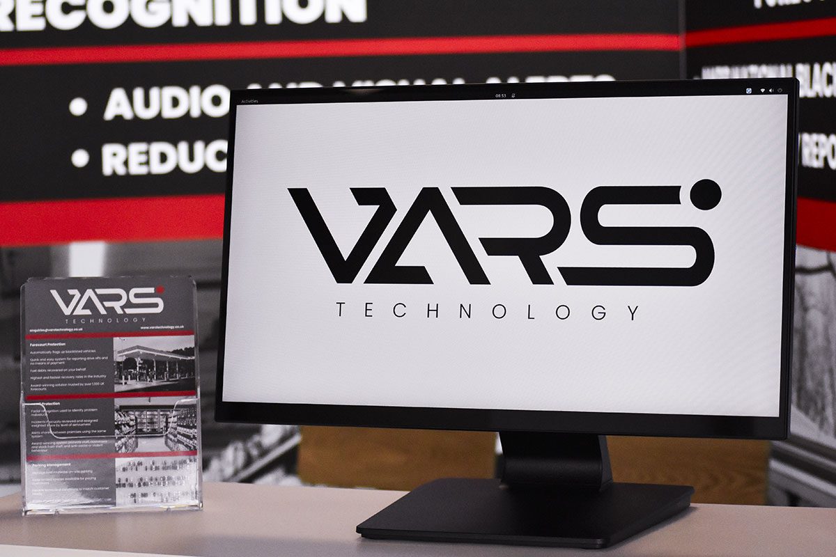 A computer screen with the VARS Technology logo on it is on a table with leaflets next to it.