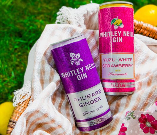 Whitley Neill enters into RTD market Cans of Whitley Neill Rhubarb & Ginger with Ginger Ale and Yuzu & White Strawberry with Lemonade sit in a wicker basket on grass with lemons around the basket.