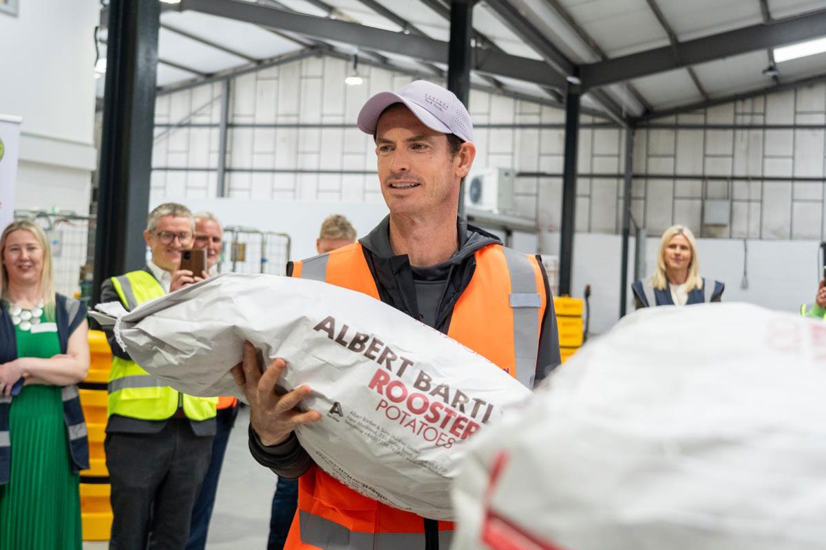 Andy Murray stands holding a sack of potatoes with the Albert Bartlett logo on the bag.