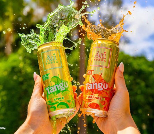 Au Vodka teams up with Tango on new cocktail cans A person holds up two cans of Au Vodka Tango one in Apple and one in Orange with the drinks spilling out the top of the cans.