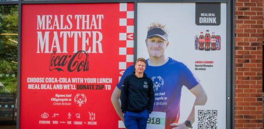 CCEP supports Special Olympics with Meals that Matter Angus Leckonby, Special Olympics GB Athlete, stands in front of the CCEP Meals that Matter promotional image which features him.
