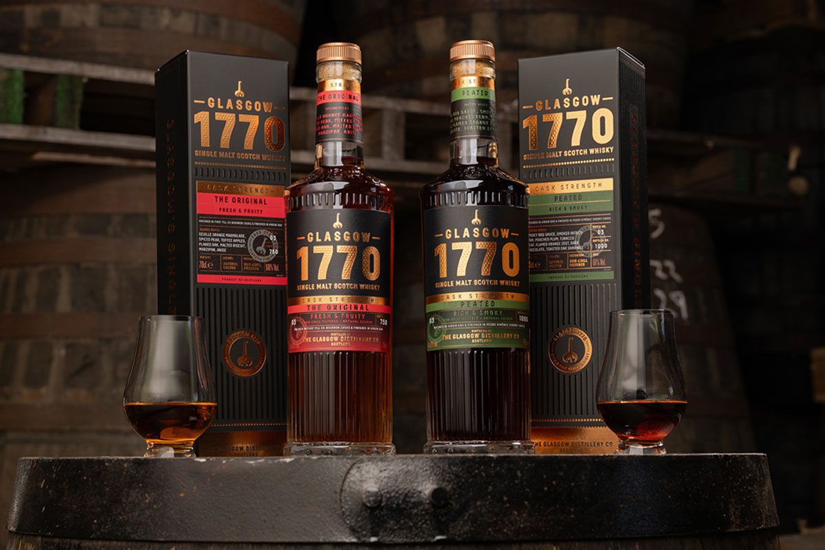 Bottles of Glasgow 1770 Batch 3 Unpeated and Peated Cask Strength stand on a whisky barrel with their outer packs next to them.