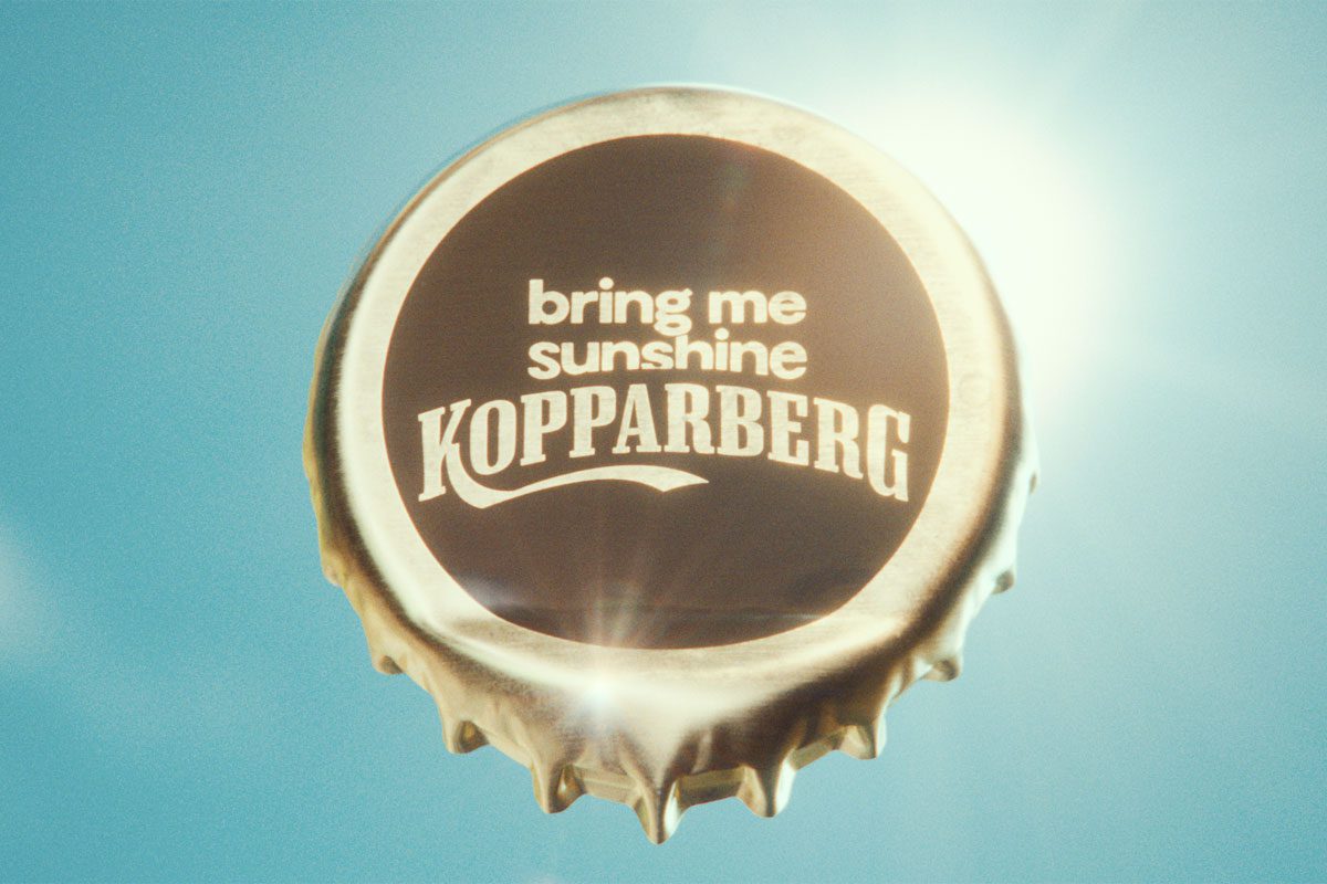 A bottle cap with the words 'bring me sunshine Kopparberg' stamped on it against a sunny sky background.