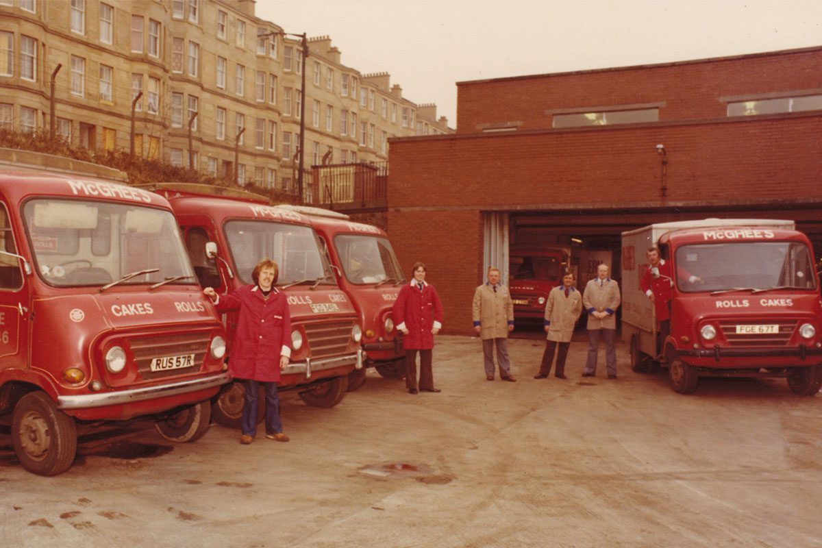 A legacy photo of members of McGhee's Bakers stand next to the firm's vans