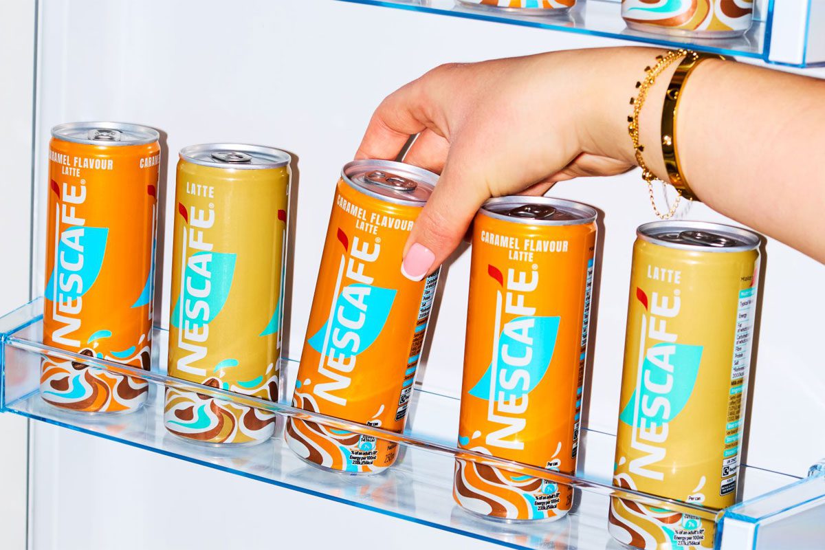 A person reaches into a fridge to lift out cans of Nescafé Iced Latte and Iced Latte Caramel.