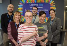 Scotmid celebrates GroceryAid Gold award Members of the Scotmid team stand together in their office holding the GroceryAid Gold trophy.