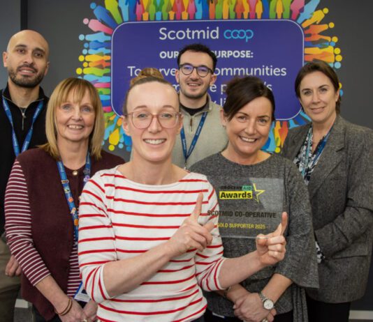 Scotmid celebrates GroceryAid Gold award Members of the Scotmid team stand together in their office holding the GroceryAid Gold trophy.