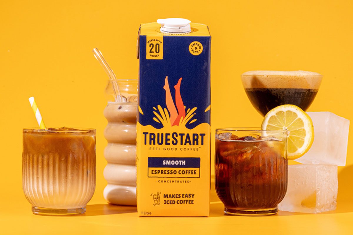 A carton of TrueStart Espresso Coffee Concentrate stands in the middle of multiple different serves using the coffee against a yellow background.
