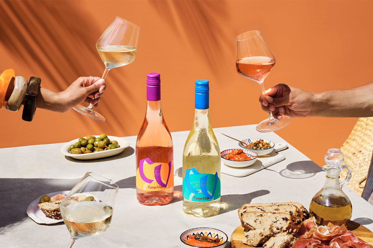 A table dinner is set with different foods and bottles of Campo Viejo Contemporary Rosa and Blanco variants.