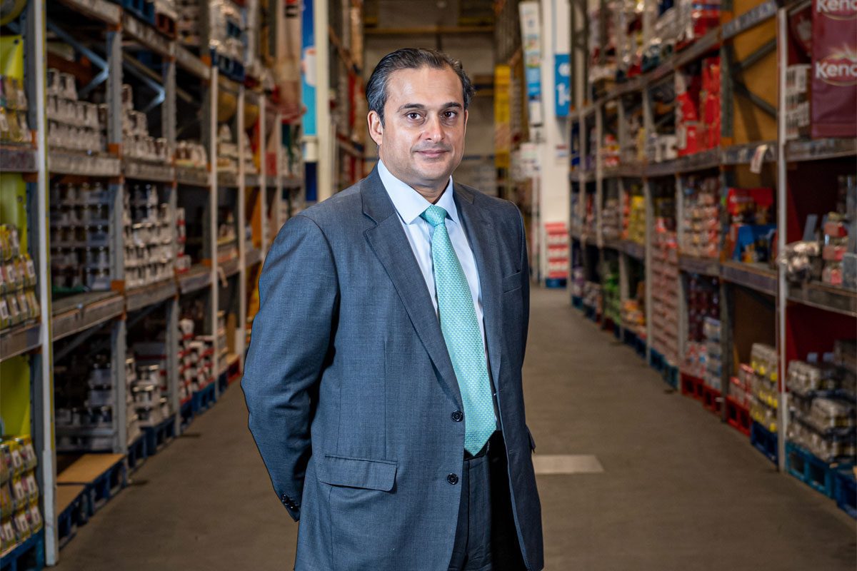 Dawood Pervez, managing director at Bestway Wholesale, stands in the middle of a wholesale aisle.