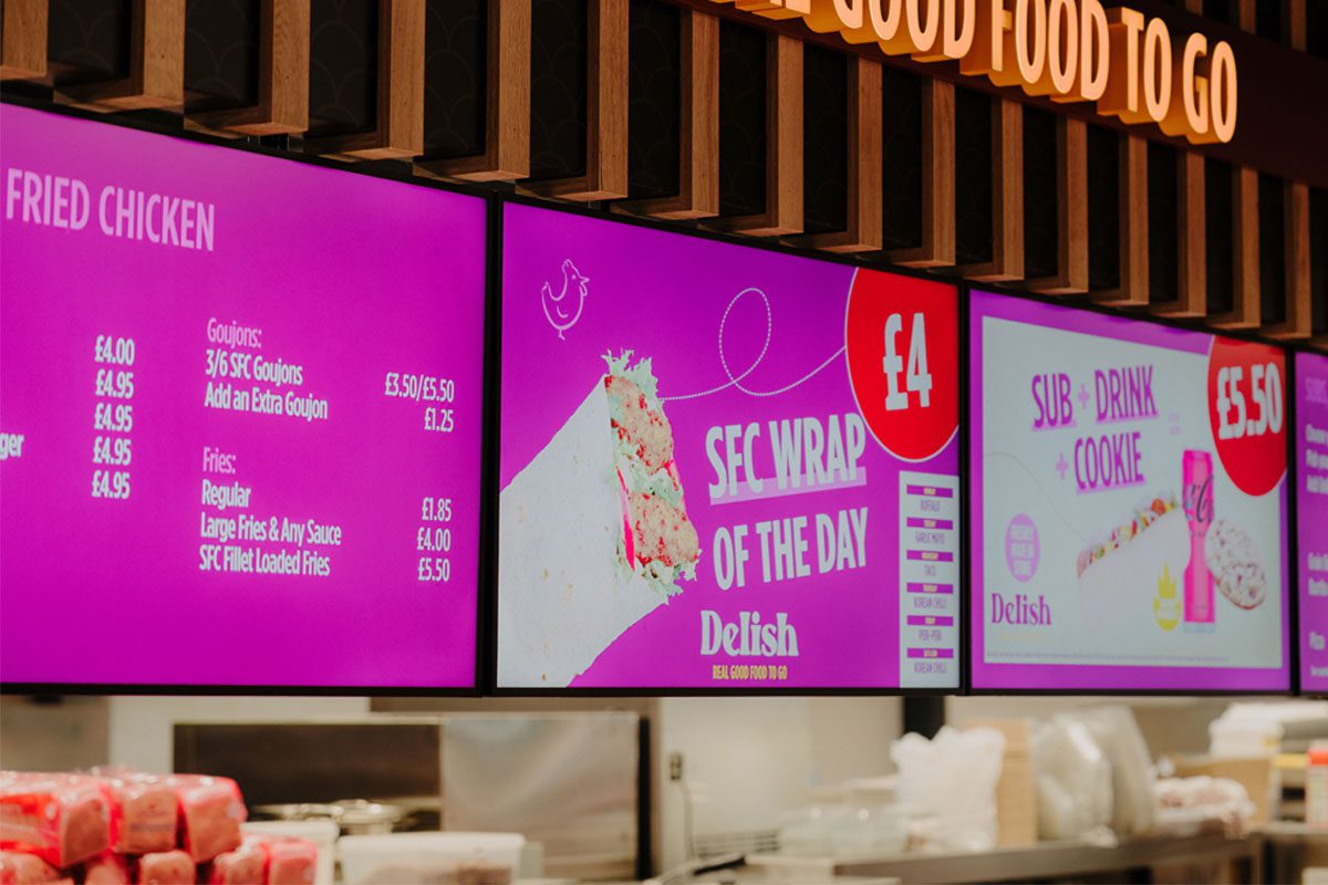 Digital screens inside a convenience store highlighting a food-to-go section from Henderson Technology.