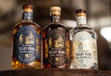 The Islay Rum Distillery takes home global accolade Bottles of The Original Islay Rum Barrel Aged, The Original Islay Rum Geal and The Original Islay Rum Peat Spiced sit on top of a barrel inside the distillery.
