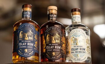 The Islay Rum Distillery takes home global accolade Bottles of The Original Islay Rum Barrel Aged, The Original Islay Rum Geal and The Original Islay Rum Peat Spiced sit on top of a barrel inside the distillery.