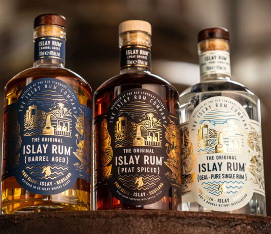 The Islay Rum Distillery takes home global accolade Bottles of The Original Islay Rum Barrel Aged, The Original Islay Rum Geal and The Original Islay Rum Peat Spiced sit on top of a barrel inside the distillery.